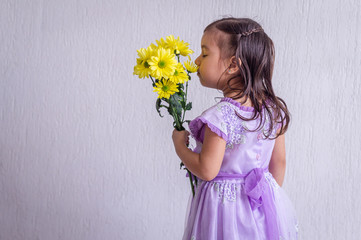 Girl in profile, smells bouquet of flowers in her left hand