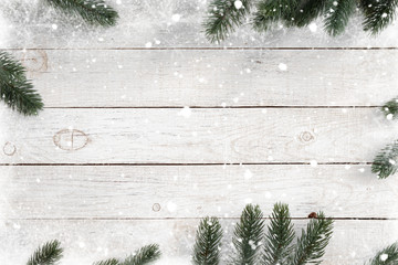 Pine leaves decorated as a frame on a white wooden background  with snowflakes. Merry Christmas and...