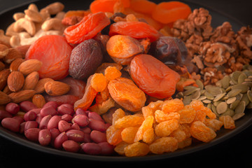 Mix of dried fruits and nuts on a black table. Close-up