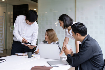 Young startup businessman holding tablet giving recommendations to coworkers during meeting at modern coworking office. Business meeting, Teamwork people concept.