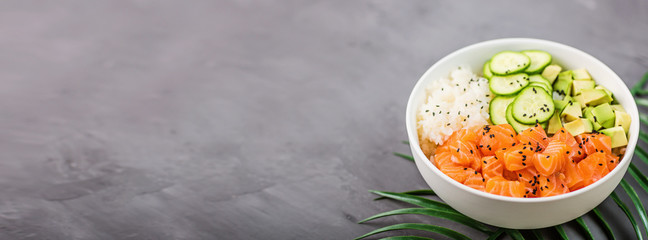 Hawaiian salmon bowl with cucumbers, avocado, sesame seeds and rice. Top view, overhead, flat lay, mock up, template. Healthy food concept