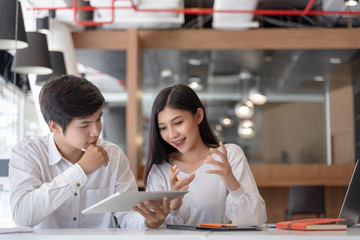 Group of asian young coworkers discussing together in comfortable office. Business people brainstorming concept.