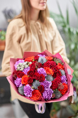 Modern floral shop. Finished work of the florist. Cute bouquet of mixed flowers in womans hands. Delivery fresh cut flower.