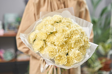 Lemon color mono bouquet of carnation in womans hands. European floral shop. the work of the...