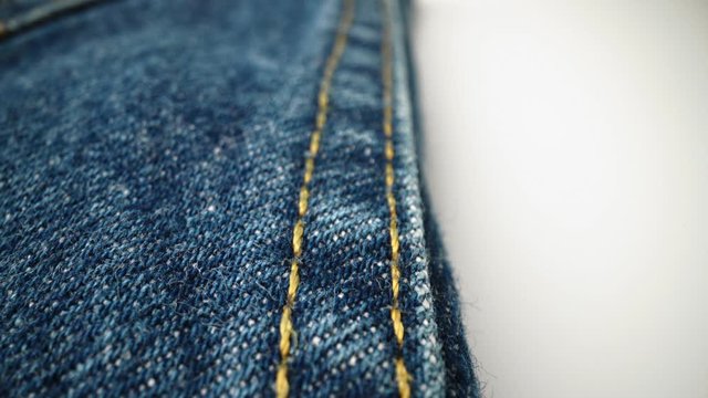 Extreme detailed of blue denim jeans cloth texture in macro dolly shot over the cloth surface. Flow view of clothing material. Textile abstract background. Vintage fashion apparel industry concept.