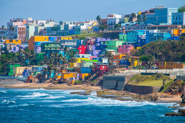 Colorful houses line the hill side overlooking the beach in San Juan, Puerto Rico. - Powered by Adobe