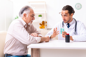 Young male doctor visiting old patient at home