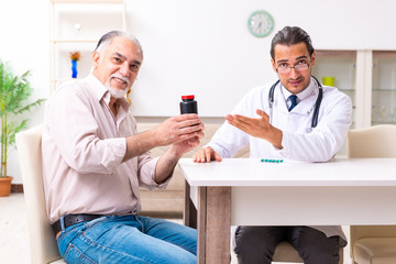 Obraz premium Young male doctor visiting old patient at home