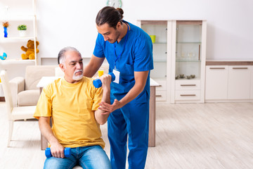 Obraz premium Young male doctor visiting old patient at home