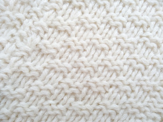 Background of wool yarn for yarn frame. White knitting yarn for handicrafts background. Knitted clothes from wool yarn.