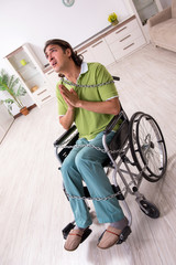 Young male invalid in wheel-chair suffering at home
