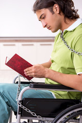 Young male invalid in wheel-chair suffering at home