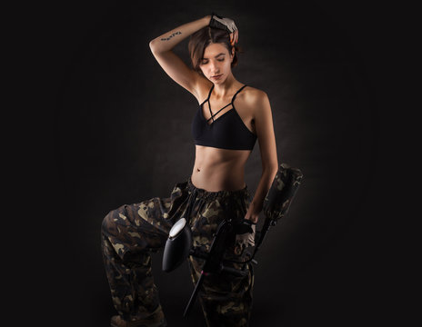 pretty woman in equipment with a paintball gun on a black background. Leisure