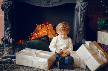 Cute little boy in a white sweater. Child by the christmas tree