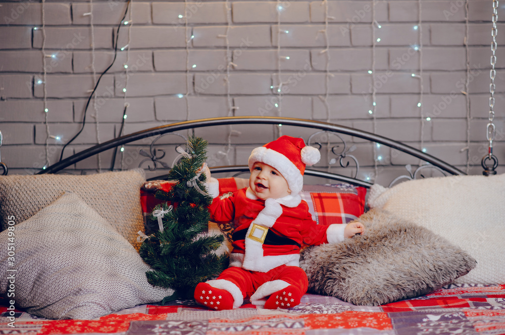 Sticker Cute little boy in a christmas costume. Child by the christmas tree