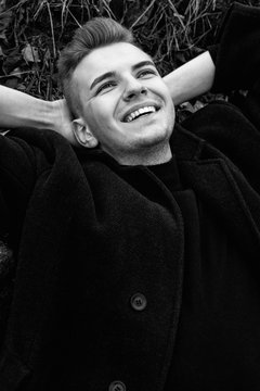 smilling close-up fashion male model in coat black and white photo, art portrait of man