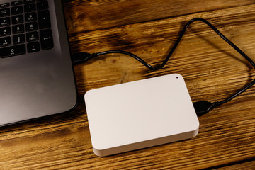 External HDD connected to laptop computer on a wooden desk. Concept of data storage