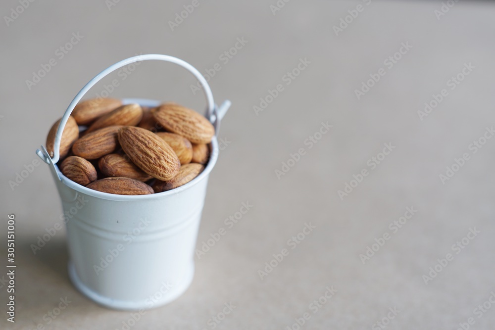 Wall mural Almond nut in white can and green leaf on wooden table background - Wall murals