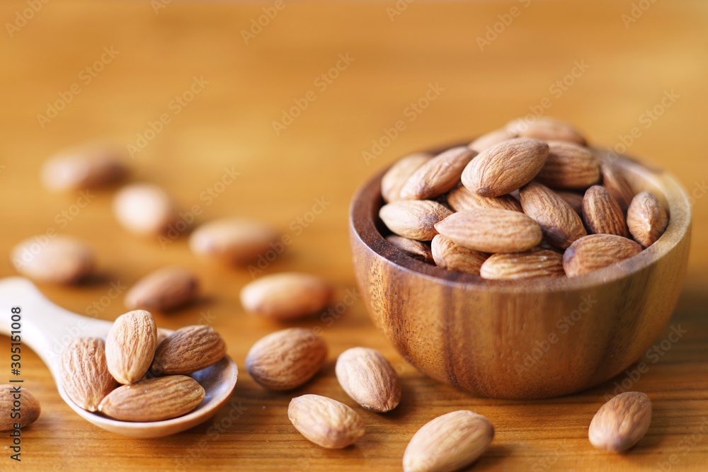 Wall mural Almond nut in wood bowl on wooden table background - Wall murals