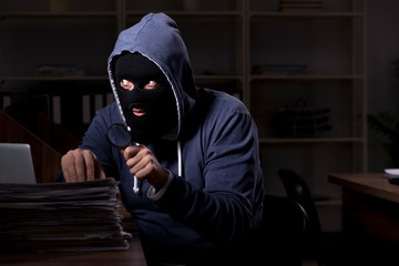 Male thief in balaclava in the office night time