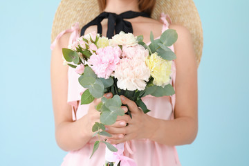 Beautiful young woman with bouquet of carnation flowers on color background, closeup