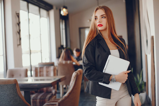 Stylish woman standing in a restaurant. Businesswoman working at the cafe. Girl use the tablet