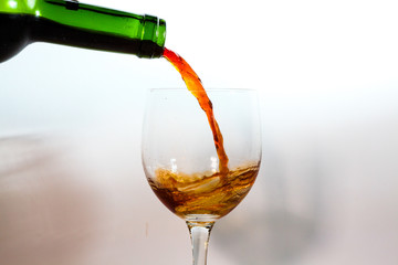 pouring red wine into glass isolated on white