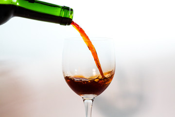 pouring red wine into glass isolated on white