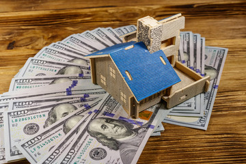 House model and U.S. one hundred dollar bills on wooden background. Property investment, home loan, house mortgage, real estate concept