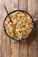 Hot rice with carrots, green peas, onions and bacon close-up in a plate. vertical top view