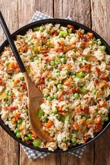 Fried rice with vegetables and bacon close-up in a plate. Vertical top view