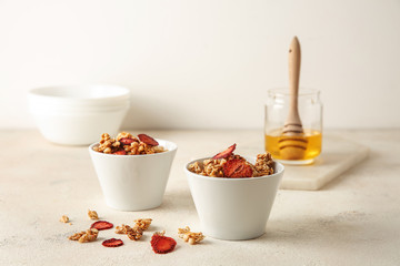 Bowls with tasty granola and berries on white table