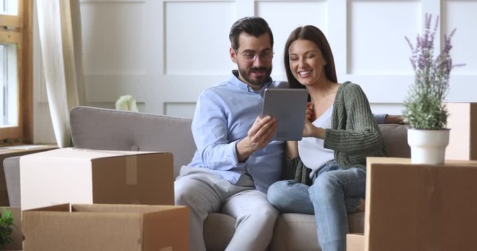 Happy 30s couple using tablet computer on moving day