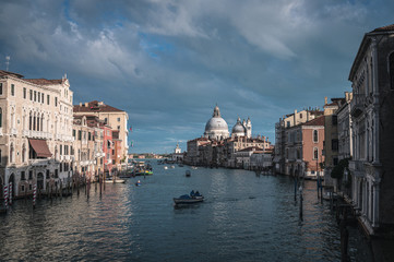 Venice Grand canal on sunset time. View of Basilica di Santa Maria della Salute, gondolas, water buses and typical Venetian houses and architecture. Beautiful and romantic Italian city.