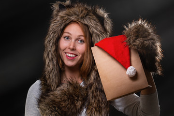 New Year. A beautiful young woman, in a fur hat with ears, and woolly mittens, smiling and holding...