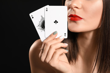 Beautiful young woman with playing cards on dark background, closeup