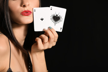Beautiful young woman with playing cards on dark background, closeup