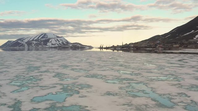 The mountainous sea coast is covered with snow with the sun the closed cloud. Place of shooting northerly coast of the Bering Sea, Chukchi region, Russia.