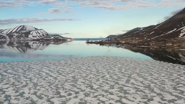 The mountainous sea coast is covered with snow with the sun the closed cloud. Place of shooting northerly coast of the Bering Sea, Chukchi region, Russia.