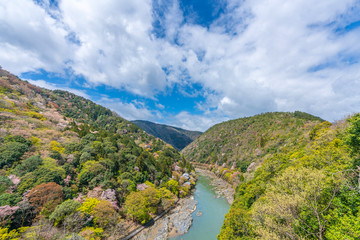 Fototapeta na wymiar Beautiful colorful forest mountains and river with blue sky view at katsura river lake to Arashiyama mountain Kyoto, Japan. idea for rest relax enjoy lifestyle