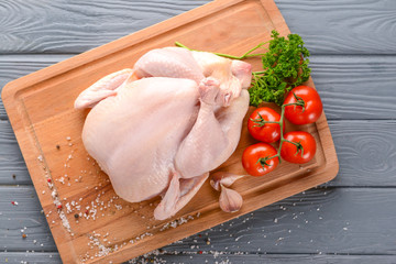 Raw chicken with spices and tomato on wooden background