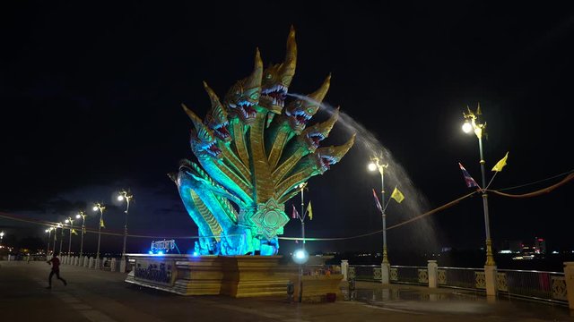 A seven headed Naga staue spouting water and illuminated at nght-time in Sri Chiang Northern Thailand.