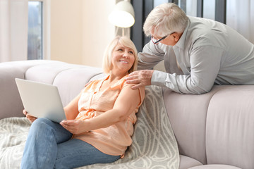 Mature couple with laptop resting at home