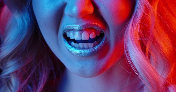 Closeup Shot Of Face Of Girl Wearing Glowing Makeup Doing A Seductive Growl In Neon Light - Nightlife Concept 4k Footage