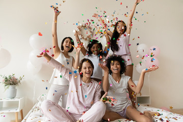 Smiling women group wear sleepwear celebrate party throw confetti up