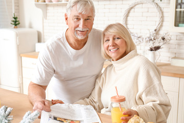 Happy mature couple having breakfast in kitchen
