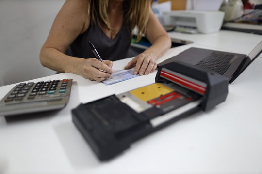 Clear image of female wrettening, signature on imprint paper with defocused of old credit card imprinter machine on the white table on the foreground