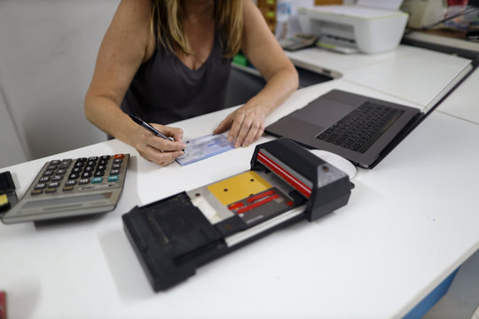 Clear image of female wrettening, signature on imprint paper and old credit card imprinter machine on the white table background
