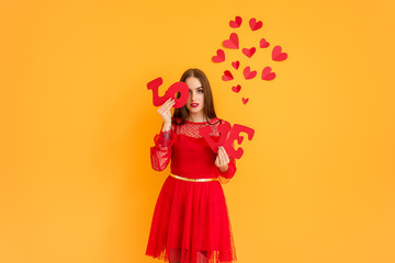 Beautiful young woman with word LOVE and hearts on color background. Valentine's Day celebration