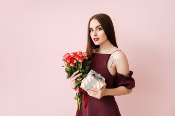 Beautiful young woman with flowers and gift on color background. Valentine's Day celebration